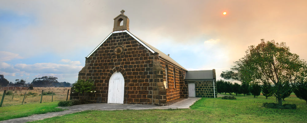 Small bluestone church with a white door at Heywood, Victoria - fine art photography print by Adam Gormley