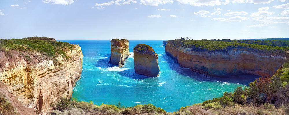 Two limestone pillars in turquoise water between cliffs near Loch Ard Gorge, Victoria - fine art photography print by Adam Gormley