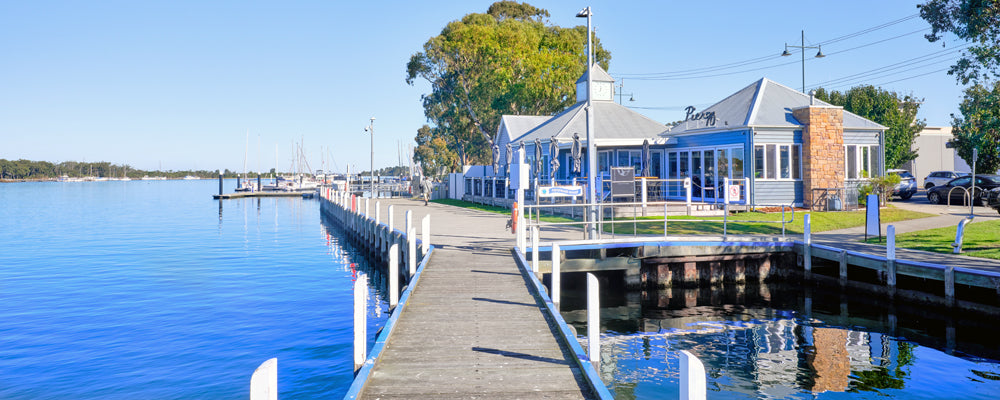 Boardwalk beside calm blue water at Paynesville, Gippsland Lakes, Victoria - fine art photography print by Adam Gormley