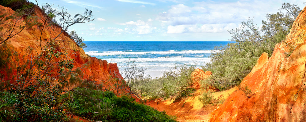 Orange and red sand walls opening to the ocean at Red Canyon, K'gari (Fraser Island), Queensland - fine art photography print by Adam Gormley