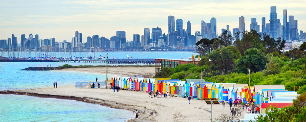 Colourful bathing boxes at Brighton Beach with the Melbourne skyline, Victoria - fine art photography print by Adam Gormley