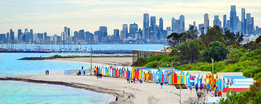 Colourful bathing boxes at Brighton Beach with the Melbourne skyline, Victoria - fine art photography print by Adam Gormley