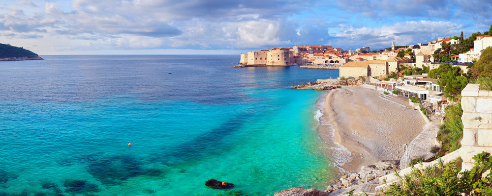 Turquoise water and pebble beach beside the Old Town walls, Dubrovnik, Croatia - fine art photography print by Adam Gormley