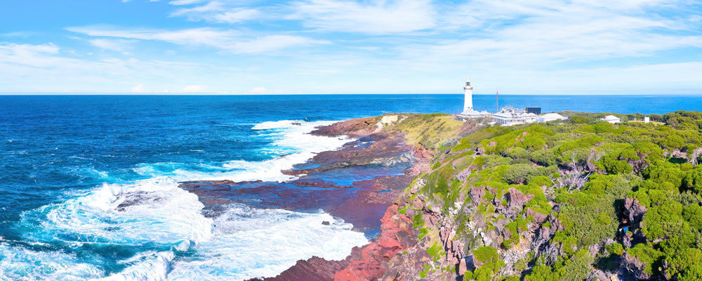 Green Cape Lighthouse above red rocks and surf, Ben Boyd National Park, New South Wales - fine art photography print by Adam Gormley