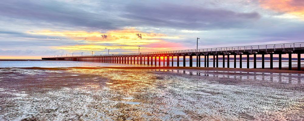 Sun rising through the pylons of Urangan Pier at low tide, Hervey Bay, Queensland - fine art photography print by Adam Gormley