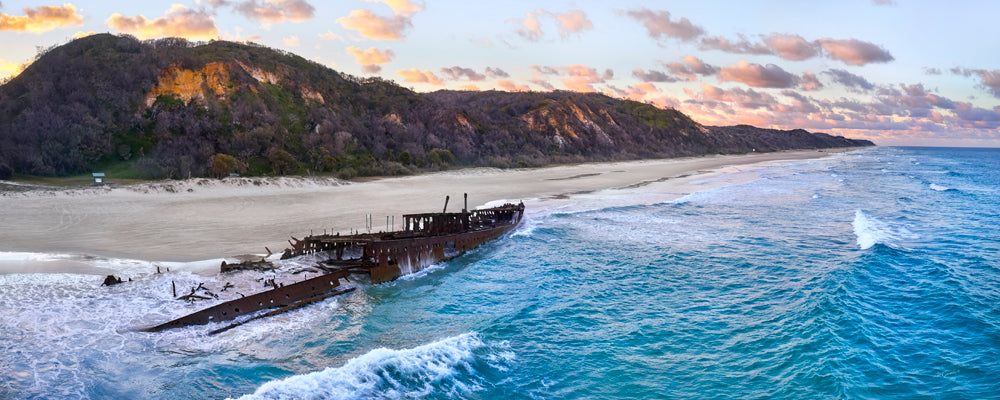 Maheno shipwreck in the surf below wooded dunes, K'gari (Fraser Island), Queensland - fine art photography print by Adam Gormley