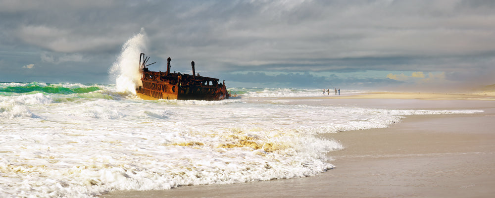 Wave exploding against the Maheno shipwreck under a grey sky, K'gari (Fraser Island), Queensland - fine art photography print by Adam Gormley