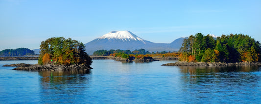 Snow-capped Mount Edgecumbe beyond forested islands in Sitka Sound, Alaska - fine art photography print by Adam Gormley