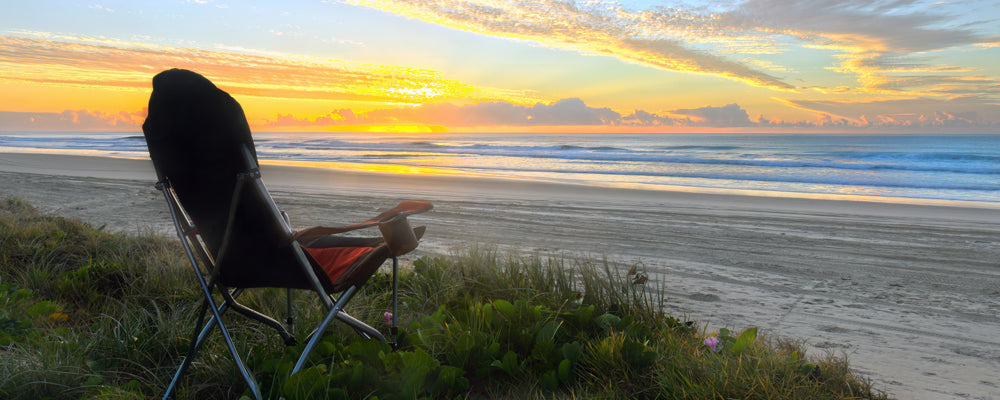 Camp chair facing the sunrise on the beach at Noosa North Shore, Queensland - fine art photography print by Adam Gormley