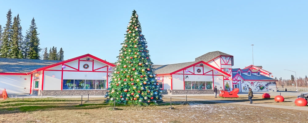 Giant decorated Christmas tree outside red and white buildings in North Pole, Alaska - fine art photography print by Adam Gormley