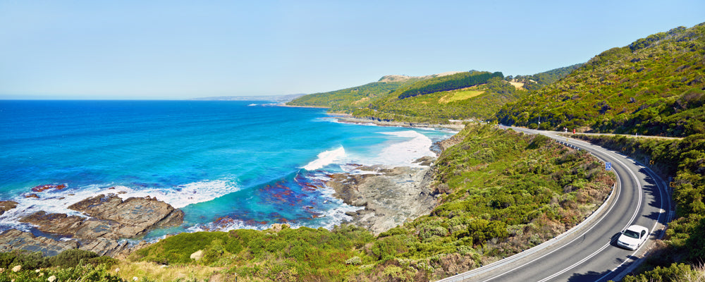 The Great Ocean Road winding around green hills above the sea, Victoria - fine art photography print by Adam Gormley