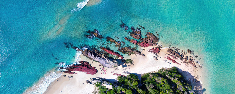 Aerial view of red rocks and turquoise water at the Pambula River mouth, New South Wales - fine art photography print by Adam Gormley