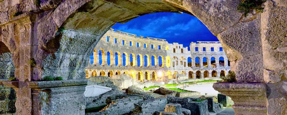 Roman amphitheatre of Pula Arena framed by a stone arch at dusk, Istria, Croatia - fine art photography print by Adam Gormley