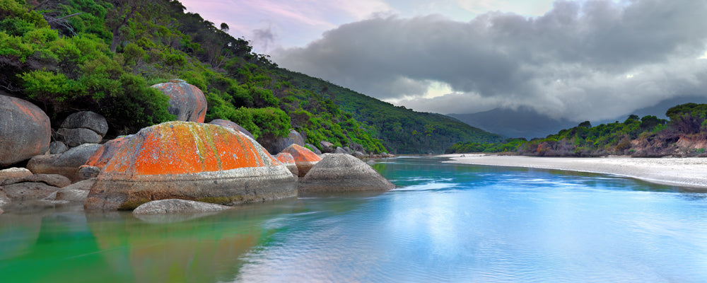 Orange granite boulders beside the calm water of Tidal River, Victoria - fine art photography print by Adam Gormley