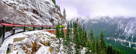 White Pass railway winding along snowy cliffs above a forested valley, Alaska - fine art photography print by Adam Gormley